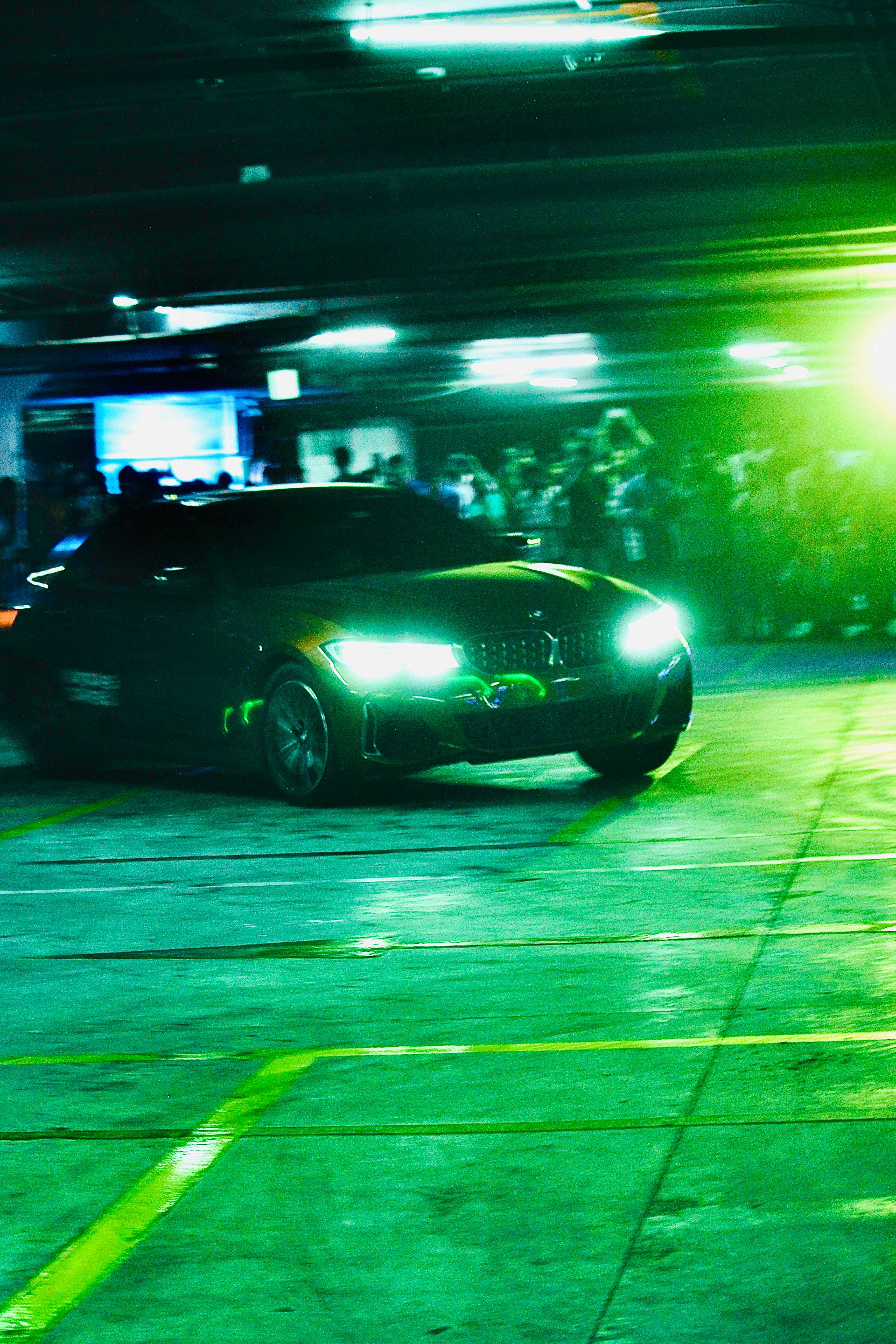 High-performance car racing on green-lit track at night
